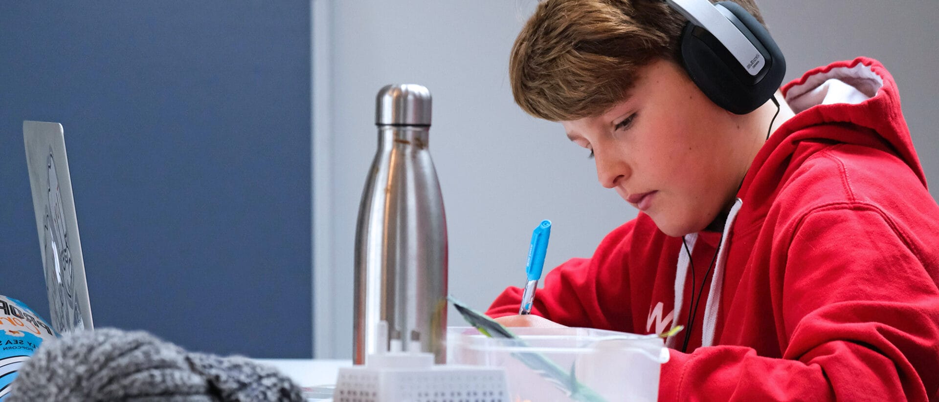 Boy at desk studying with headphones on